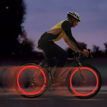 Load image into Gallery viewer, Two LED lights clipped to bicycle spokes, glowing in multiple colours to improve night visibility.
