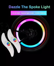 Load image into Gallery viewer, Two LED lights clipped to bicycle spokes, glowing in multiple colours to improve night visibility.
