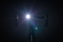 Load image into Gallery viewer, Bicycle headlight shining brightly in a dark setting
