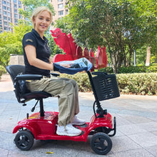 Load image into Gallery viewer, Mobility scooter equipped with a clear handlebar rain cover, shown in use on a paved walkway surrounded by greenery.
