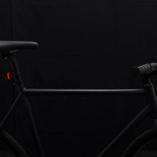 Load image into Gallery viewer, Bookman Curve bike light mounted on the rear of a black bicycle.
