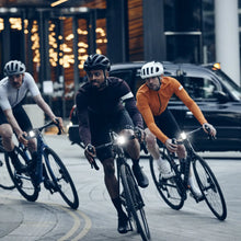 Load image into Gallery viewer, Cyclists riding with front bicycle lights during an urban evening ride
