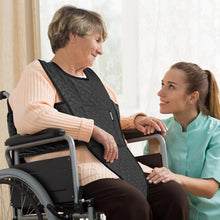 Load image into Gallery viewer, Elderly woman in wheelchair wearing black safety harness vest while caregiver kneels beside her, providing support and assistance at home.
